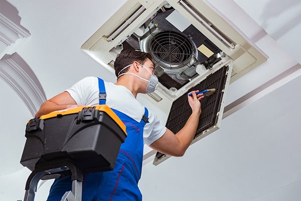 Worker repairing ceiling air conditioning unit
